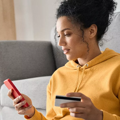 Woman holding a smartphone in one hand and a credit card in the other