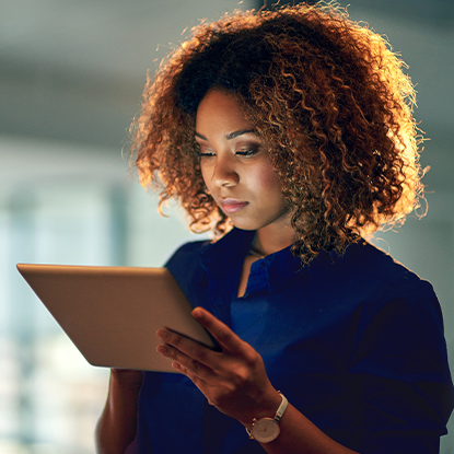 Woman talking on a cellphone while working on a laptop with boxes on a table